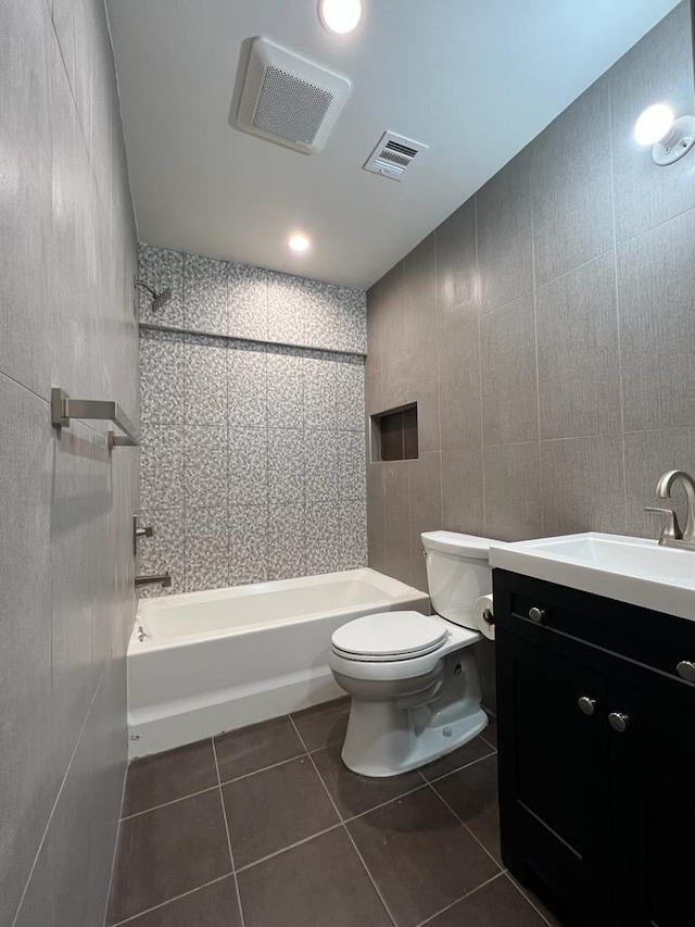 full bathroom featuring vanity, tile patterned floors, washtub / shower combination, toilet, and tile walls