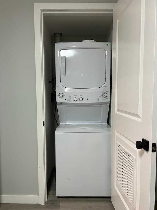 laundry room with hardwood / wood-style floors and stacked washer and clothes dryer