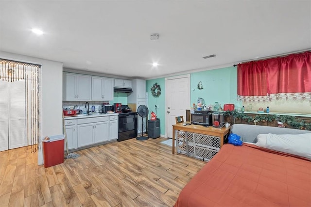 kitchen featuring decorative backsplash, electric range, sink, and light wood-type flooring