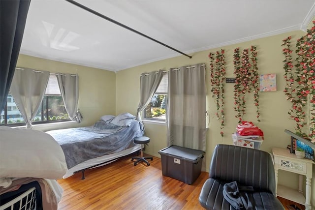 bedroom with light hardwood / wood-style floors, ornamental molding, and multiple windows