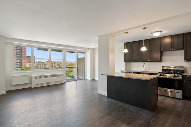 kitchen featuring stainless steel gas range, sink, hanging light fixtures, radiator, and light stone countertops