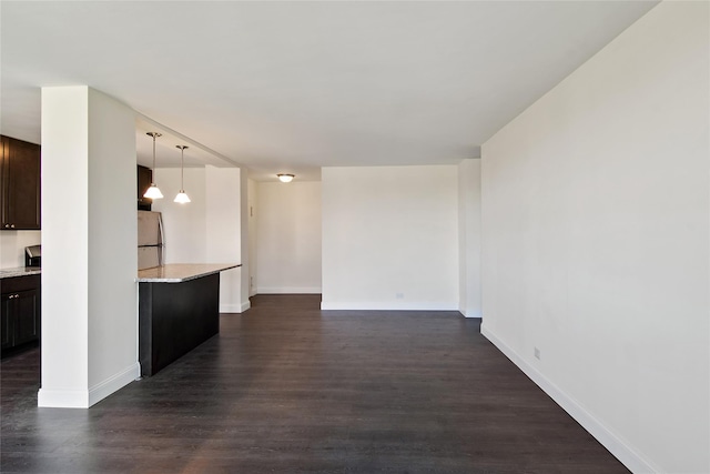 kitchen with stainless steel refrigerator, dark brown cabinetry, dark hardwood / wood-style flooring, and hanging light fixtures