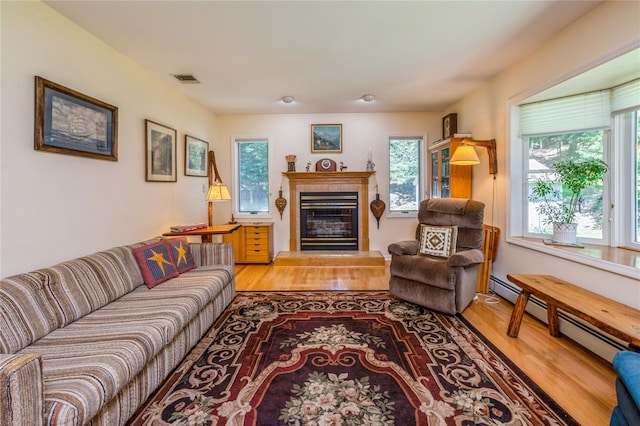 210 Bulsontown Rd, Stony Point, NY 10980 - living room with wood finished floors, a baseboard heating unit, plenty of natural light, and a tiled fireplace