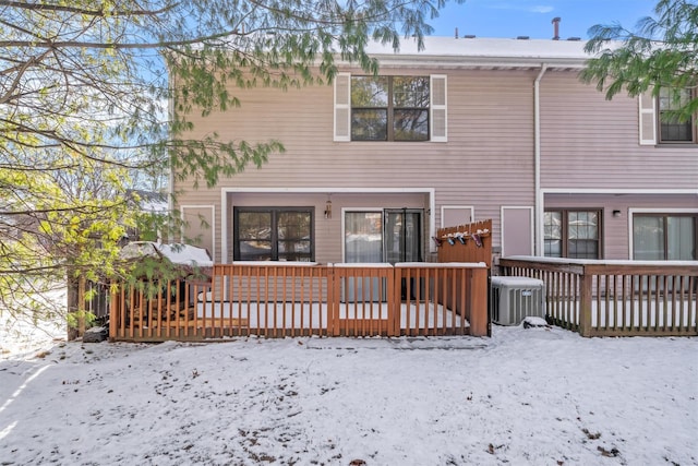 snow covered house with cooling unit and a wooden deck