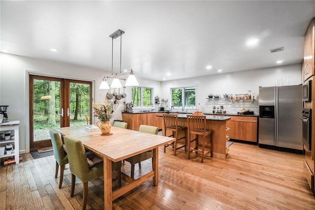 dining space with french doors and light hardwood / wood-style floors