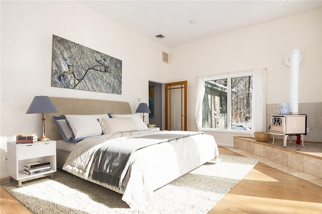 bedroom with hardwood / wood-style floors and a wood stove