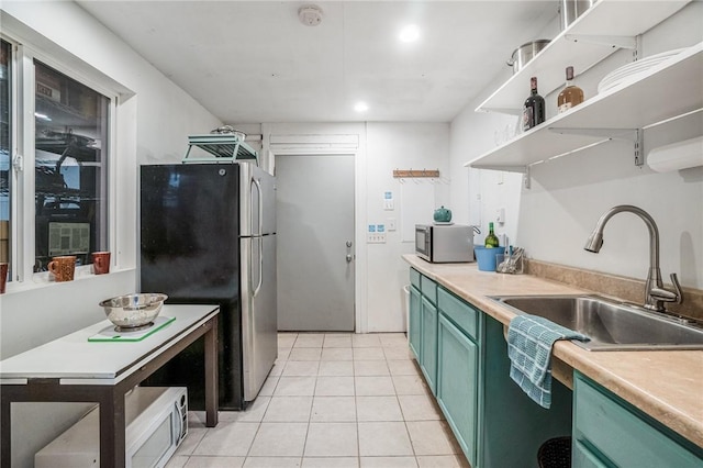 kitchen with sink, light tile patterned floors, stainless steel appliances, and green cabinetry