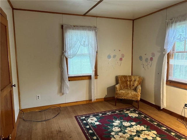 living area with hardwood / wood-style floors, plenty of natural light, and crown molding