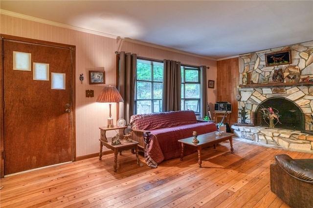 living room featuring a stone fireplace, crown molding, and light hardwood / wood-style flooring