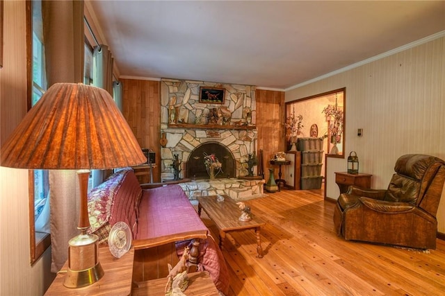 living room with crown molding, light wood-type flooring, and a fireplace