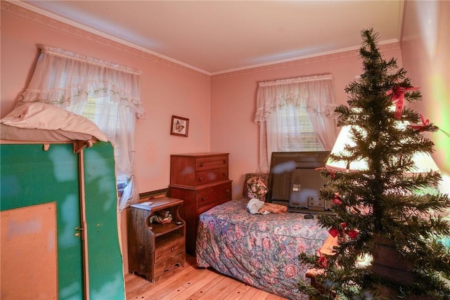 bedroom with hardwood / wood-style flooring, crown molding, and multiple windows