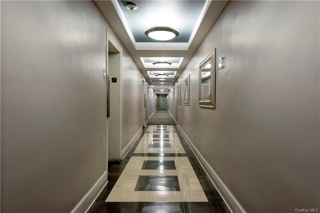 hall with tile patterned flooring and a raised ceiling