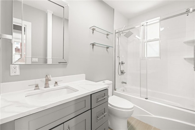 full bathroom with shower / bath combination with glass door, vanity, toilet, and a healthy amount of sunlight