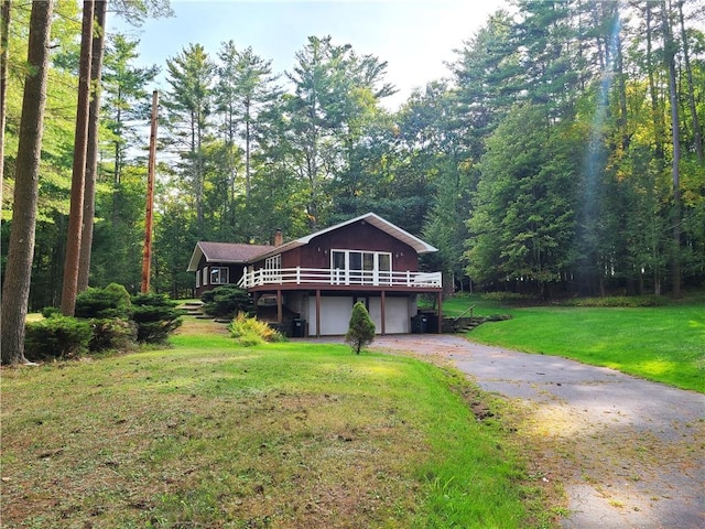 front of property with a garage, a front lawn, and a wooden deck