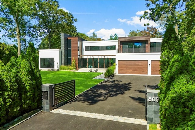 contemporary house with a front yard, a balcony, and a garage