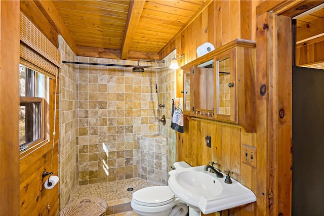 bathroom with sink, wood walls, toilet, tiled shower, and wood ceiling