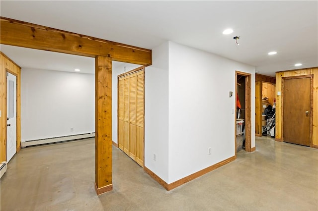 empty room featuring wood walls and a baseboard heating unit