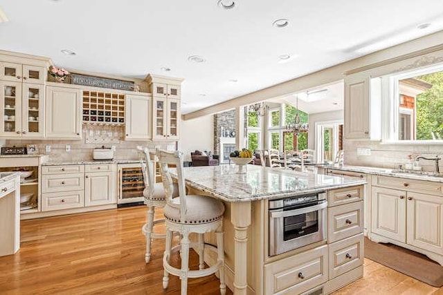 kitchen with a center island, light hardwood / wood-style floors, beverage cooler, and a breakfast bar area