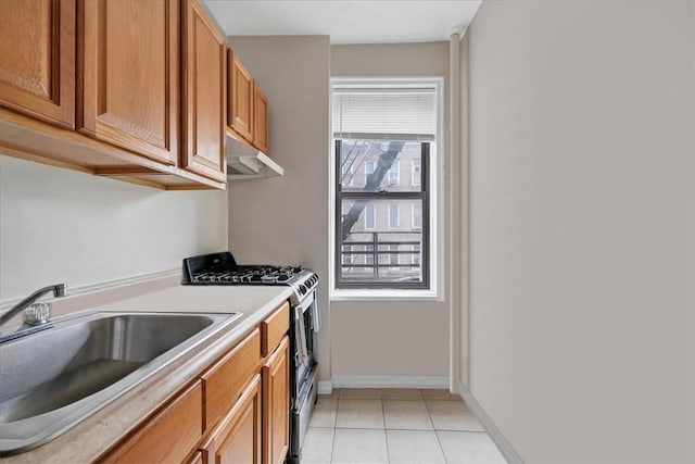 kitchen with light tile patterned flooring, gas range, and sink