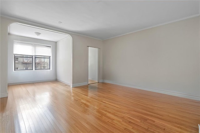 spare room featuring light wood-type flooring and crown molding