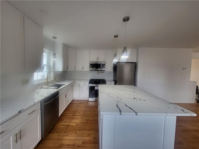 kitchen with sink, stainless steel appliances, a kitchen island, wood-type flooring, and white cabinets