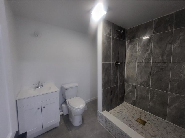 bathroom featuring tile patterned floors, vanity, toilet, and tiled shower