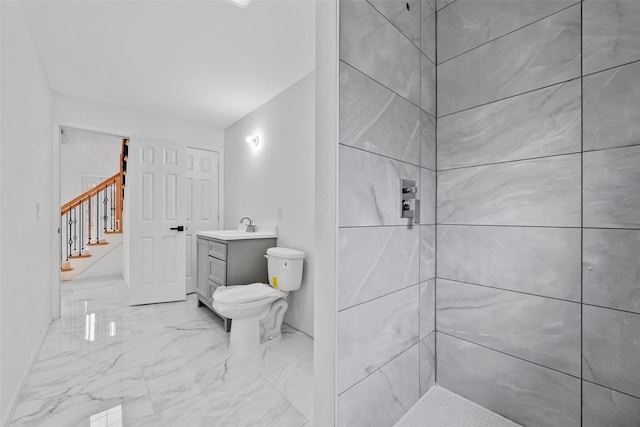 bathroom featuring marble finish floor, vanity, toilet, and tiled shower
