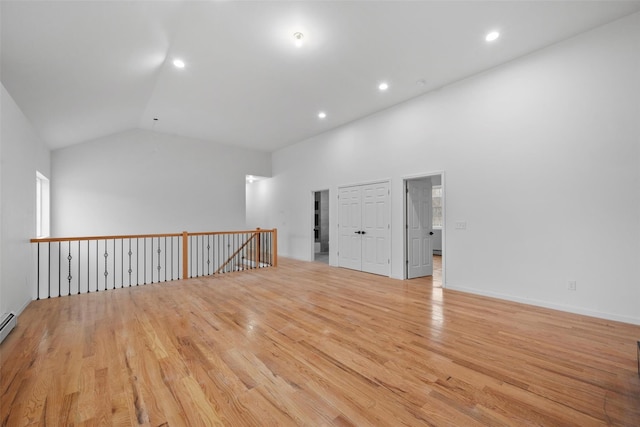 unfurnished room featuring lofted ceiling, wood finished floors, recessed lighting, and baseboard heating
