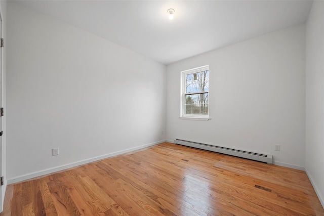 unfurnished room featuring a baseboard radiator, baseboards, and wood finished floors
