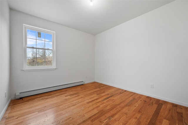 unfurnished room with baseboards, light wood-style flooring, and a baseboard heating unit