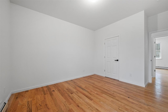 spare room with light wood-style flooring, baseboards, and a baseboard heating unit