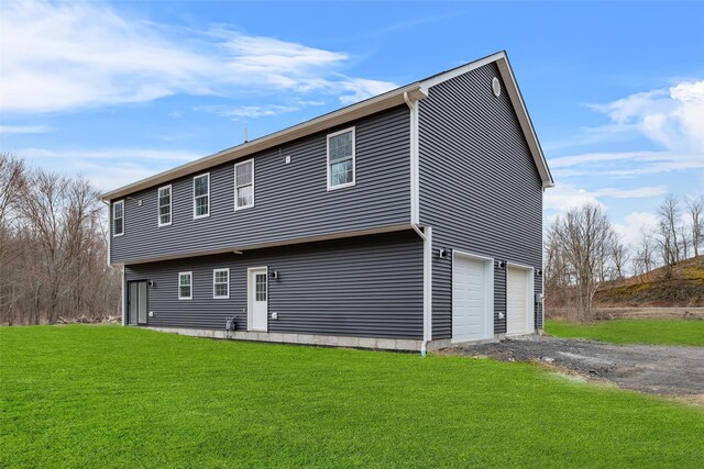 back of property with driveway, a yard, and an attached garage