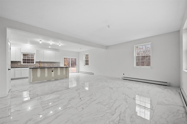 unfurnished living room with marble finish floor, baseboard heating, plenty of natural light, and a baseboard heating unit