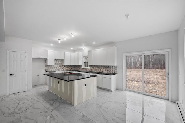 kitchen with a baseboard radiator, marble finish floor, dark countertops, and tasteful backsplash