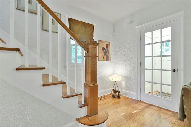 stairs featuring a textured wall, hardwood / wood-style floors, and baseboards