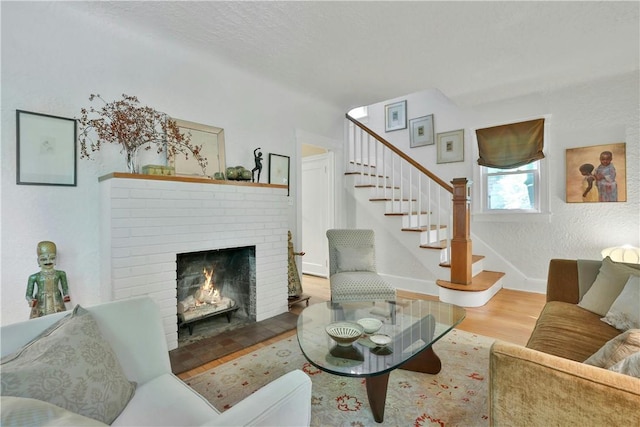 living room with stairs, baseboards, a fireplace, and wood finished floors