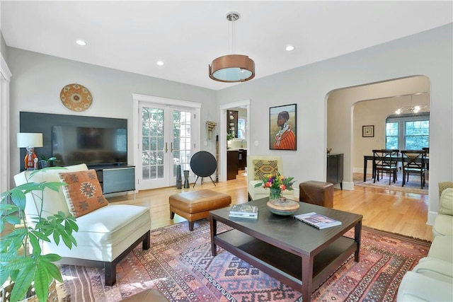 living area with a healthy amount of sunlight, arched walkways, and french doors