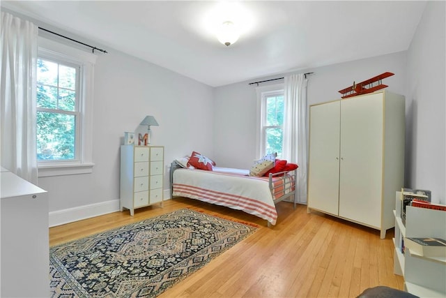 bedroom featuring baseboards, multiple windows, and light wood finished floors