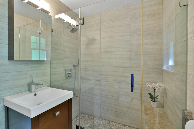 bathroom with a shower stall, vanity, and tile walls