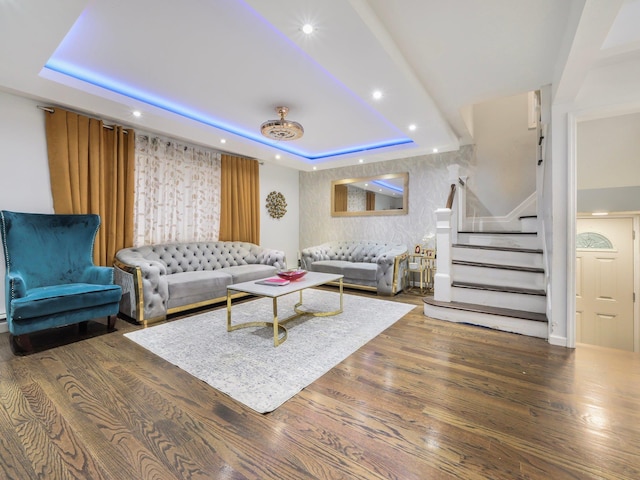 living room with a raised ceiling and dark wood-type flooring