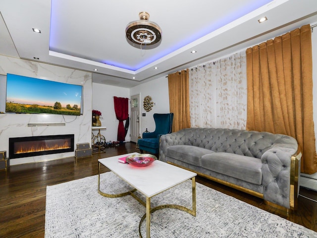 living room featuring a tray ceiling and dark wood-type flooring