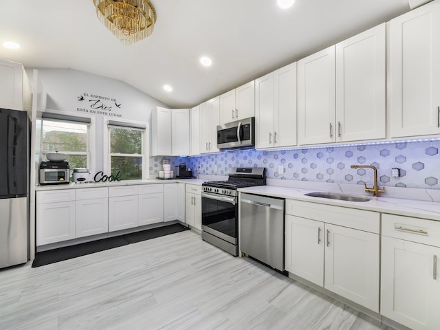 kitchen with sink, stainless steel appliances, tasteful backsplash, white cabinets, and light wood-type flooring