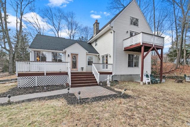 rear view of house featuring a deck and a lawn