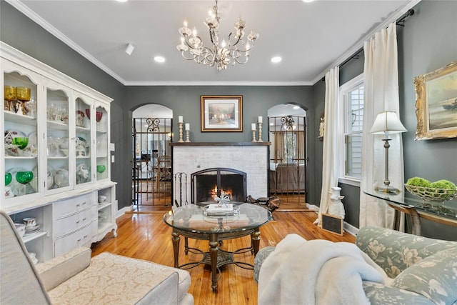 living room featuring light hardwood / wood-style flooring, crown molding, a fireplace, and a chandelier