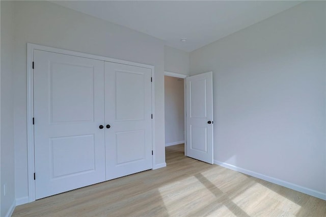 unfurnished bedroom with a closet and light wood-type flooring