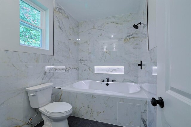 bathroom with tile patterned floors, a relaxing tiled tub, toilet, and tile walls