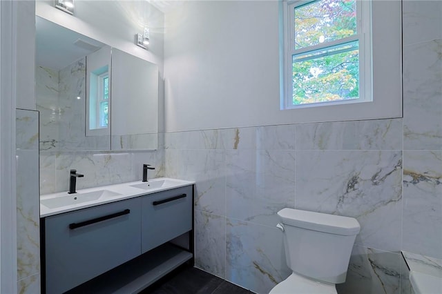 bathroom with vanity, toilet, and tile walls