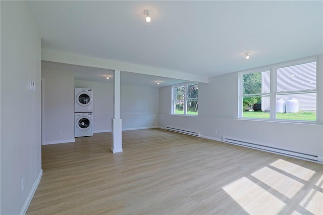 interior space with light wood-type flooring, stacked washer and dryer, and baseboard heating