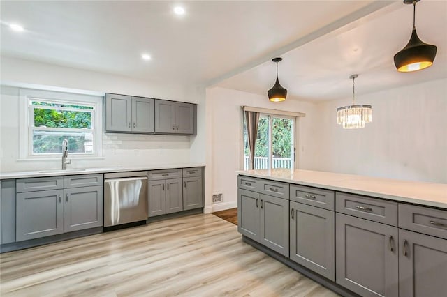 kitchen with gray cabinetry, stainless steel dishwasher, decorative light fixtures, and light wood-type flooring