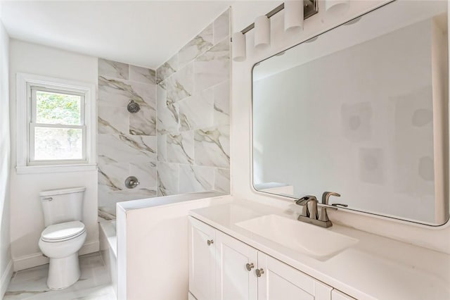 bathroom with a tile shower, vanity, and toilet